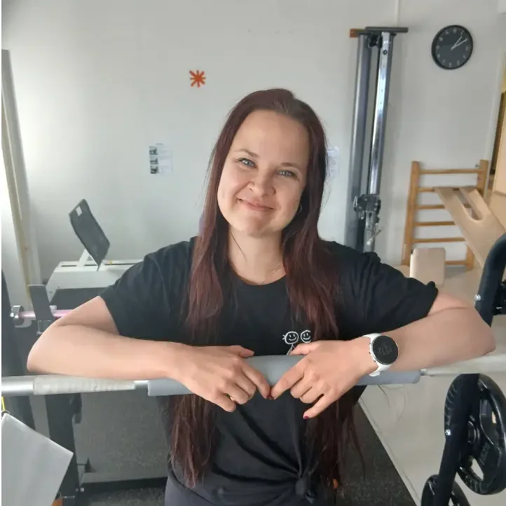 Malaryn personal trainer Heli Paajanen katsoo kameraan ja hymyilee kuntosalilaitteen ääressä.